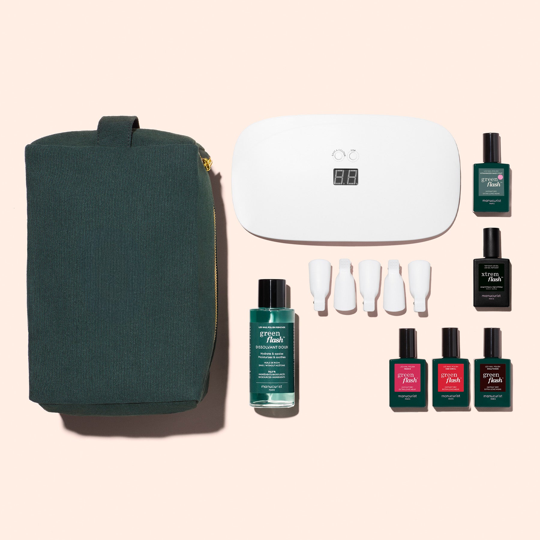 The Manucurist Starter Kit, featuring a green toiletry bag, LED nail lamp, nail polish bottles, gel polish kits, white nail tools, and cleanser, is arranged on beige for an ultra-glossy manicure.