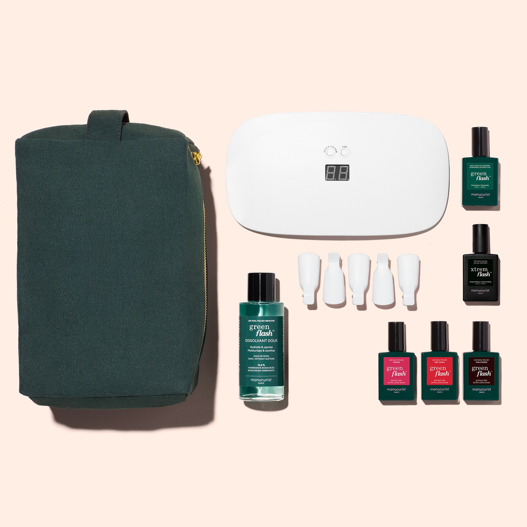 The Manucurist Starter Kit, featuring a green toiletry bag, LED nail lamp, nail polish bottles, gel polish kits, white nail tools, and cleanser, is arranged on beige for an ultra-glossy manicure.