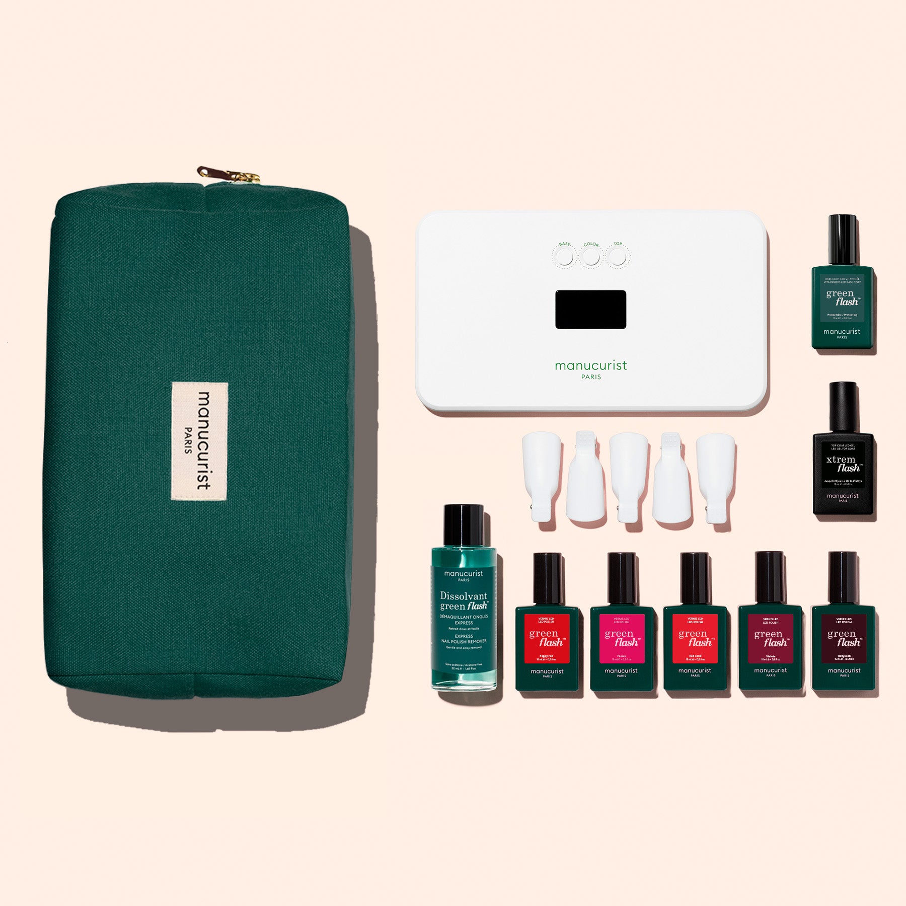 The Manucurist Super Starter Kit features a green zip pouch, white LED nail lamp, remover, six polishes including Green Flash gel in green and pink, a Vitaminized Base Coat, and four white caps on a light pink background.