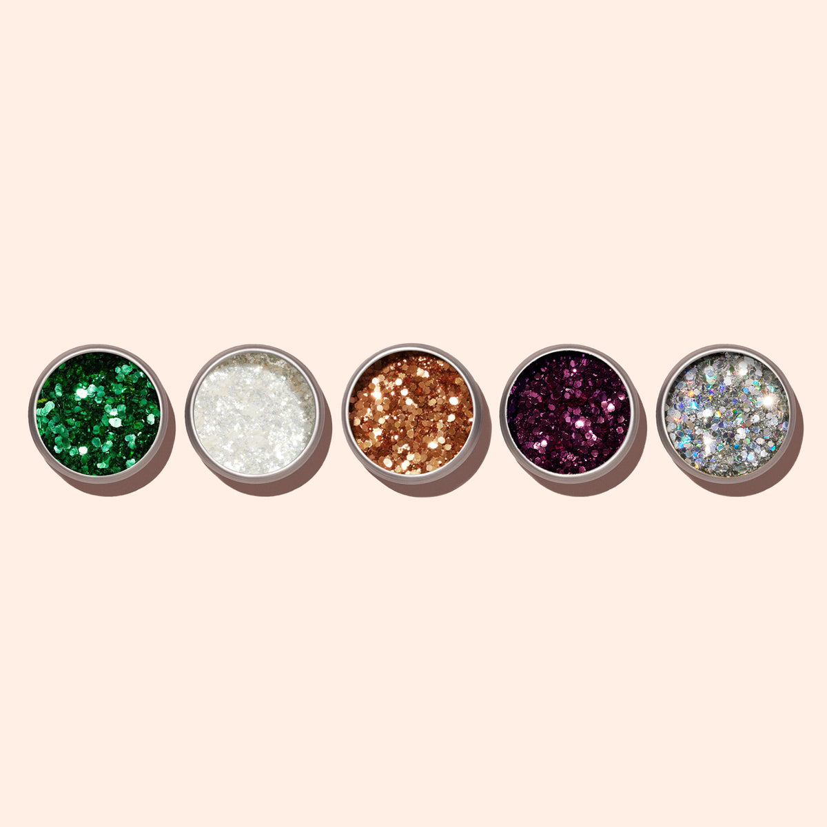 Five small round containers of Manucurist Copper biodegradable glitter, ideal for nail art, are arranged in a row on a light beige background.
