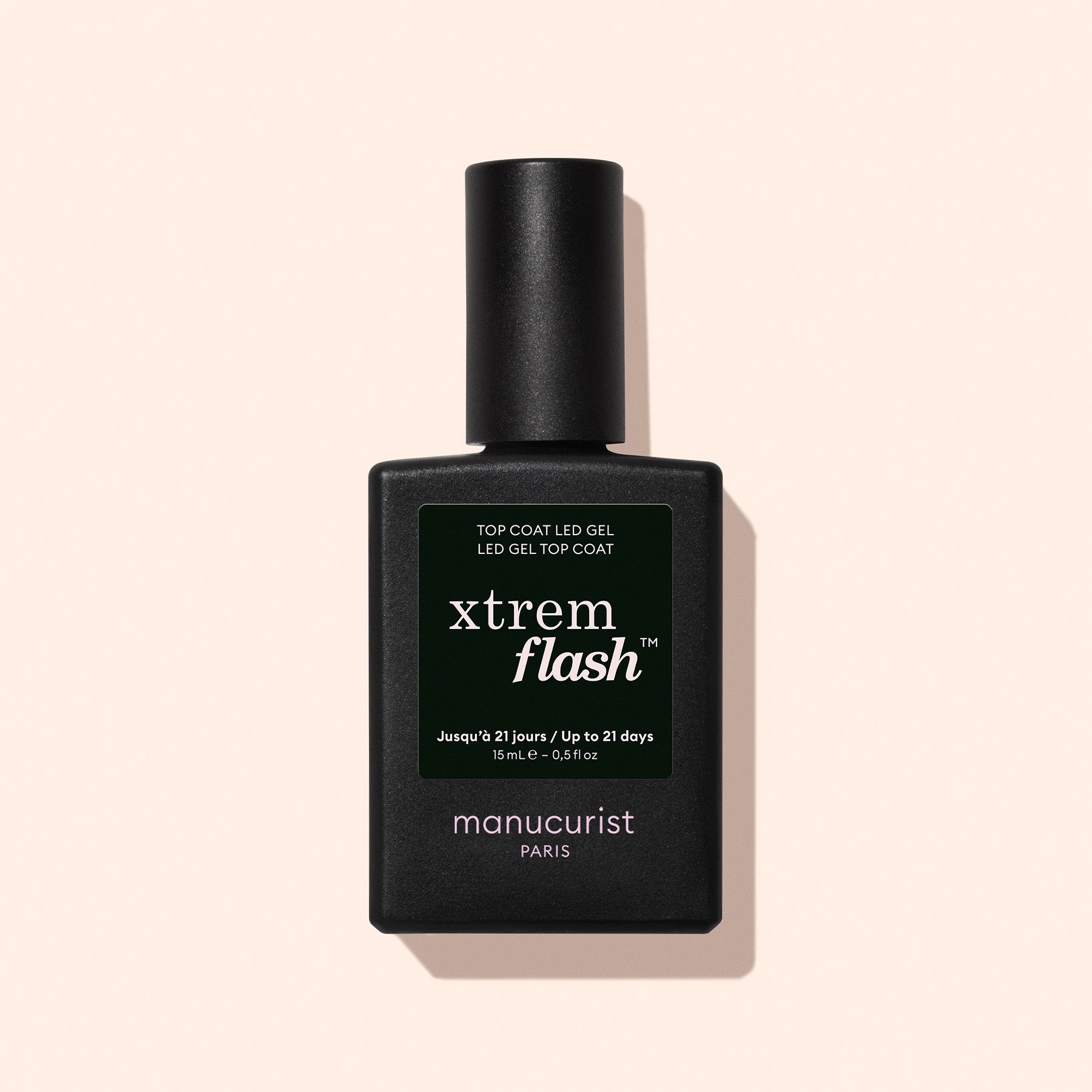 A black rectangular bottle of Manucurist Xtrem Flash™ Gel Top Coat stands upright against a pale beige background, offering a long-lasting manicure with easy, express removal.