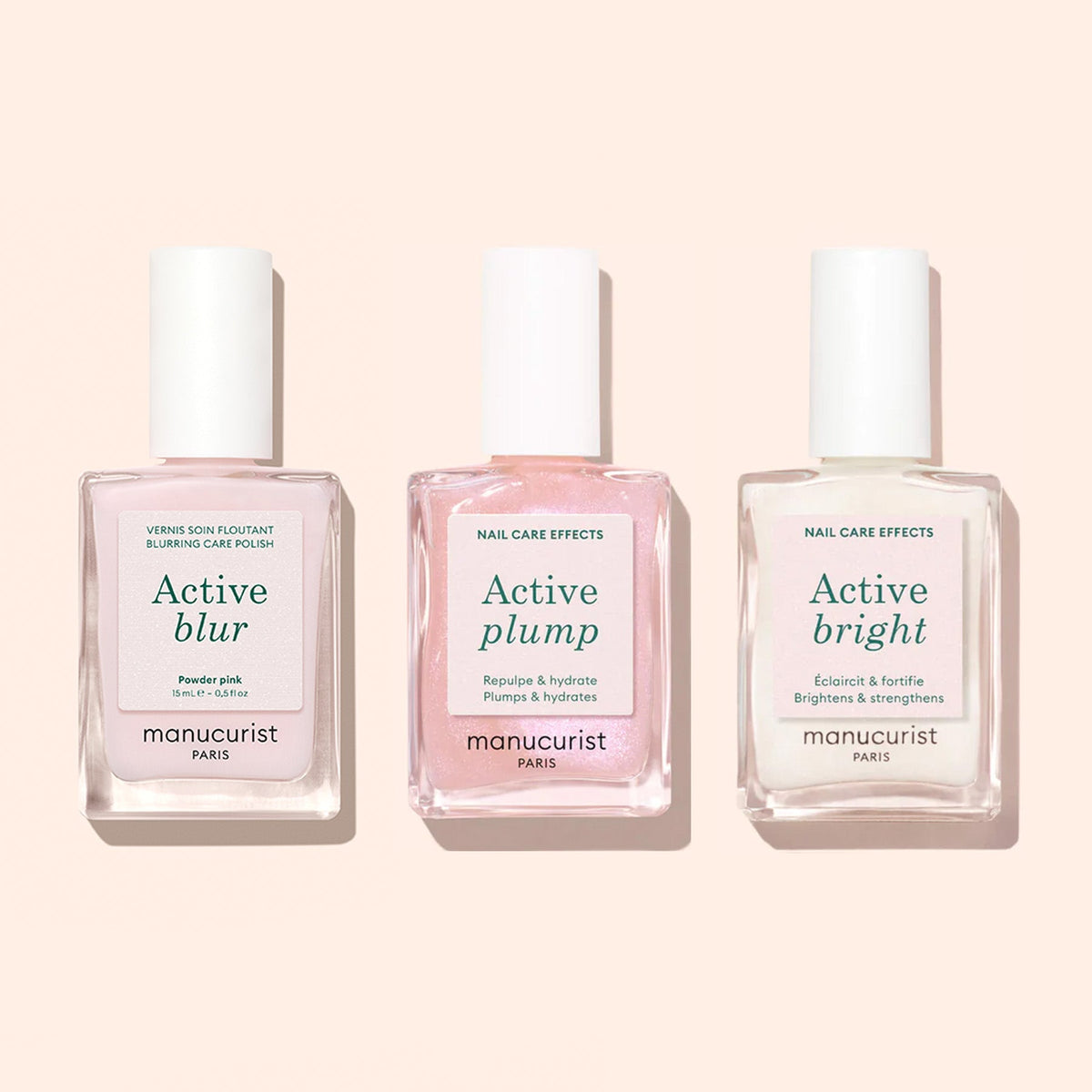 Three bottles of Manucurist nail care—Active™ Blur (pale pink), Active Plump (light pink), and Active Bright (clear)—each labeled with their unique benefits, are displayed on a light beige background. Discover the perfect blurring polish for a flawless finish, an effective nail strengthener, and more essential formulas from Manucurist to elevate your manicure routine.
