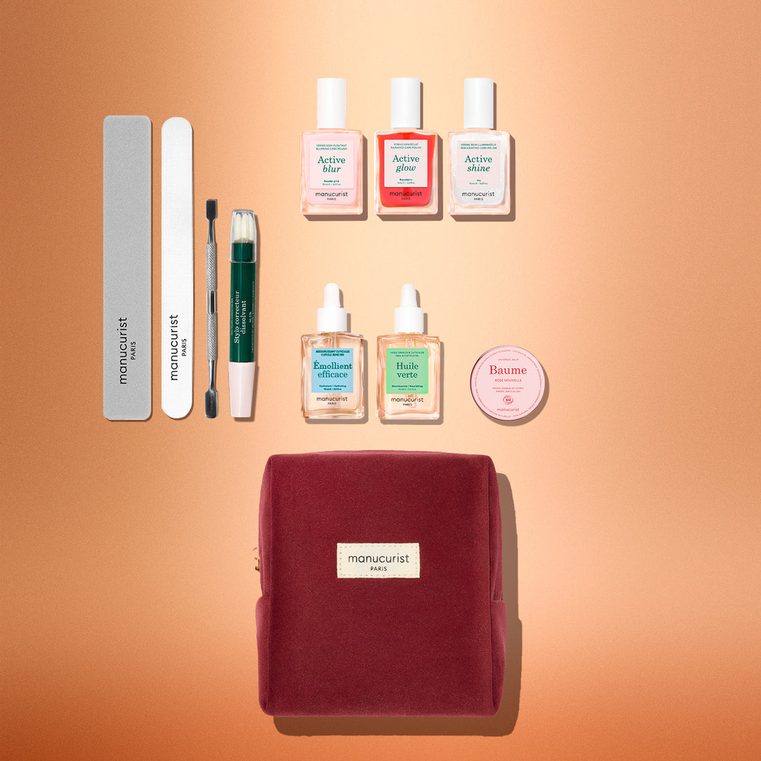 The Manucurist Active™ Ultimate Kit Gift Set features three nail polishes, two dropper bottles, a round balm tin, two nail files, a cuticle pusher, and a correction pen arranged above a velvet cosmetic bag.