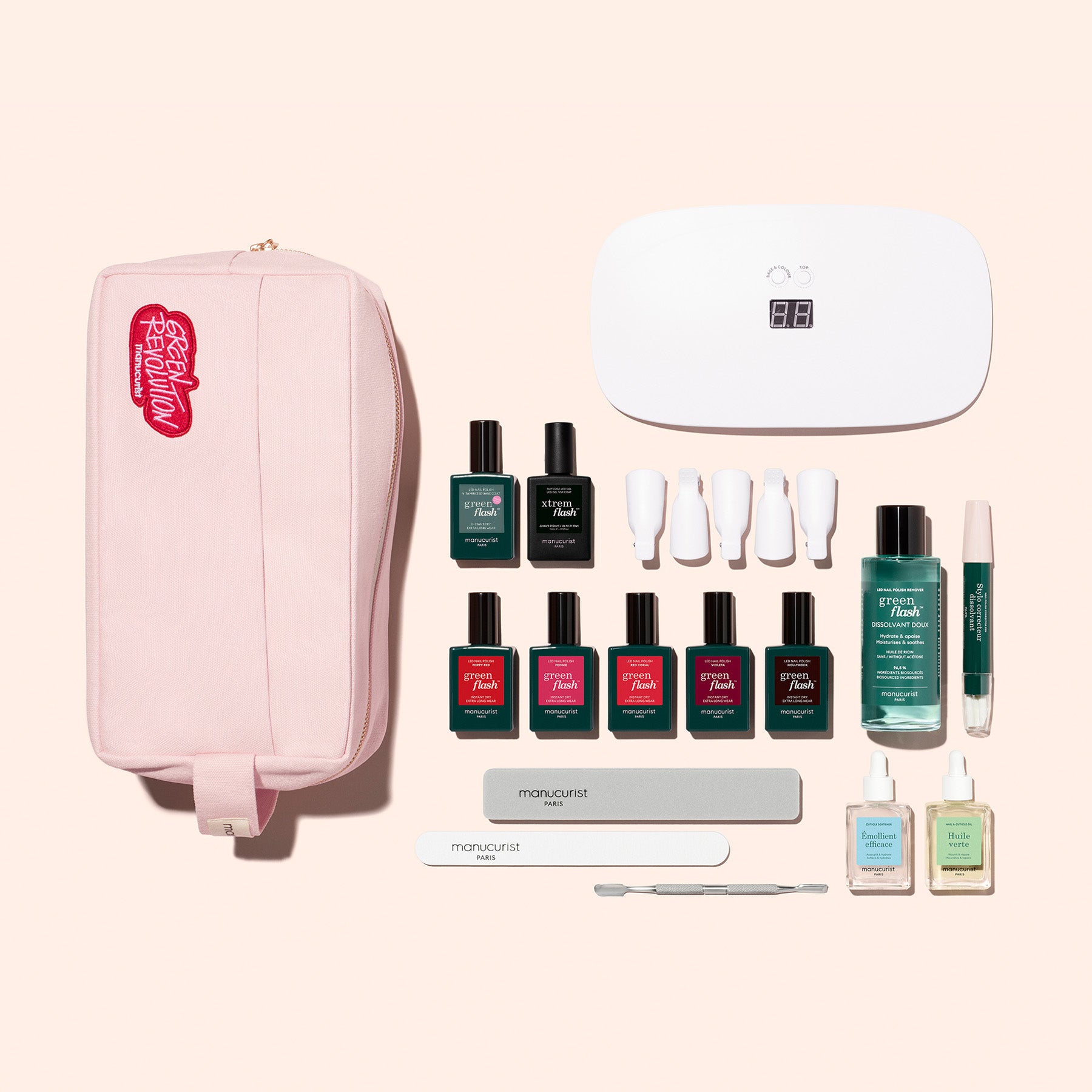 The Manucurist Super Addict Kit includes a pink zippered pouch beside manicure essentials: a UV lamp, multicolor gel polishes, vitaminized base coat, cuticle pusher, nail files, buffer blocks, cleanser, remover, and green liquid in a clear bottle.