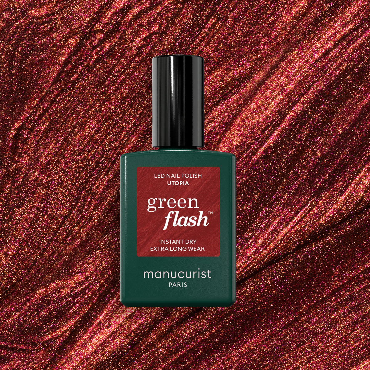 A bottle of Manucurist’s Utopia Green Flash LED gel polish stands out against a sparkling red glitter background, its green bottle with a black cap and red label showcasing the gel&
