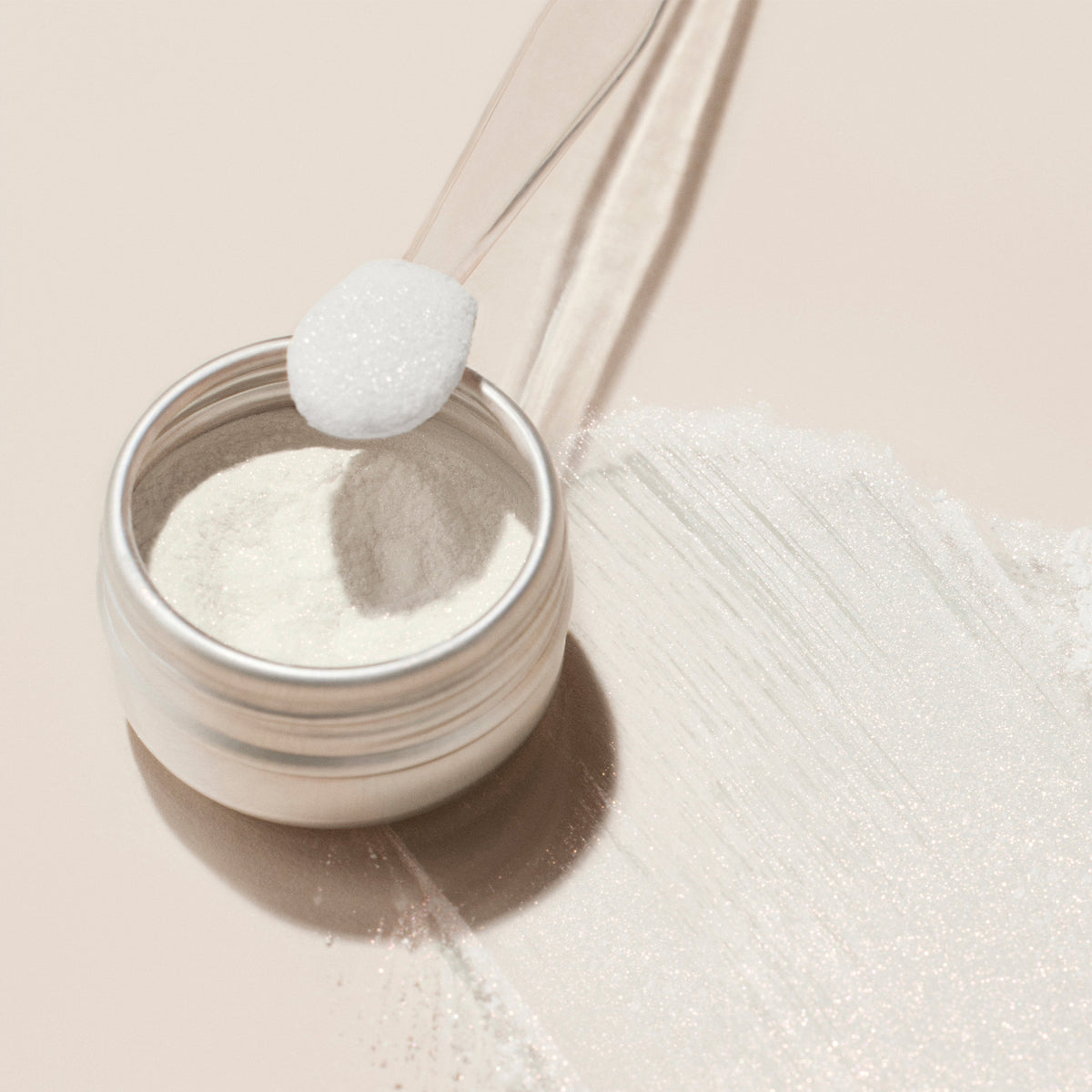 A jar of Manucurist White Glazed Effect Powder with a clear scoop and spilled powder on a beige surface—ideal for creating the signature white glazed finish in glam manicures.