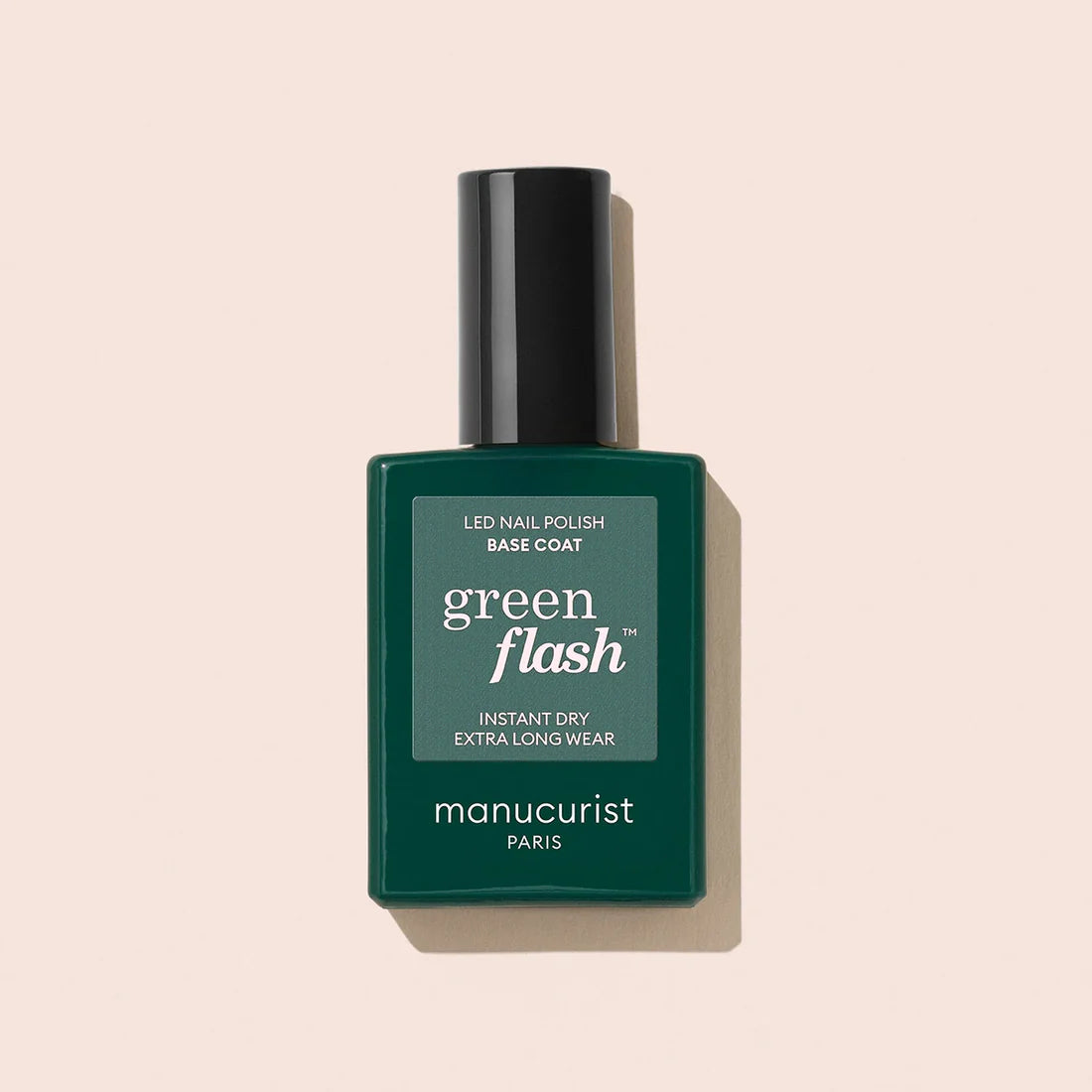 A bottle of Manucurist Base Coat in a dark green rectangular bottle with a black cap is shown on a light beige background.