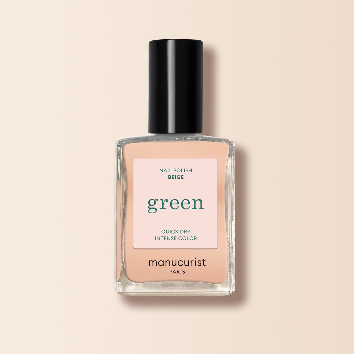 A bottle of Manucurist Beige nail polish, featuring quick dry and intense color, with a black cap and minimalist label, is shown against a light beige background.