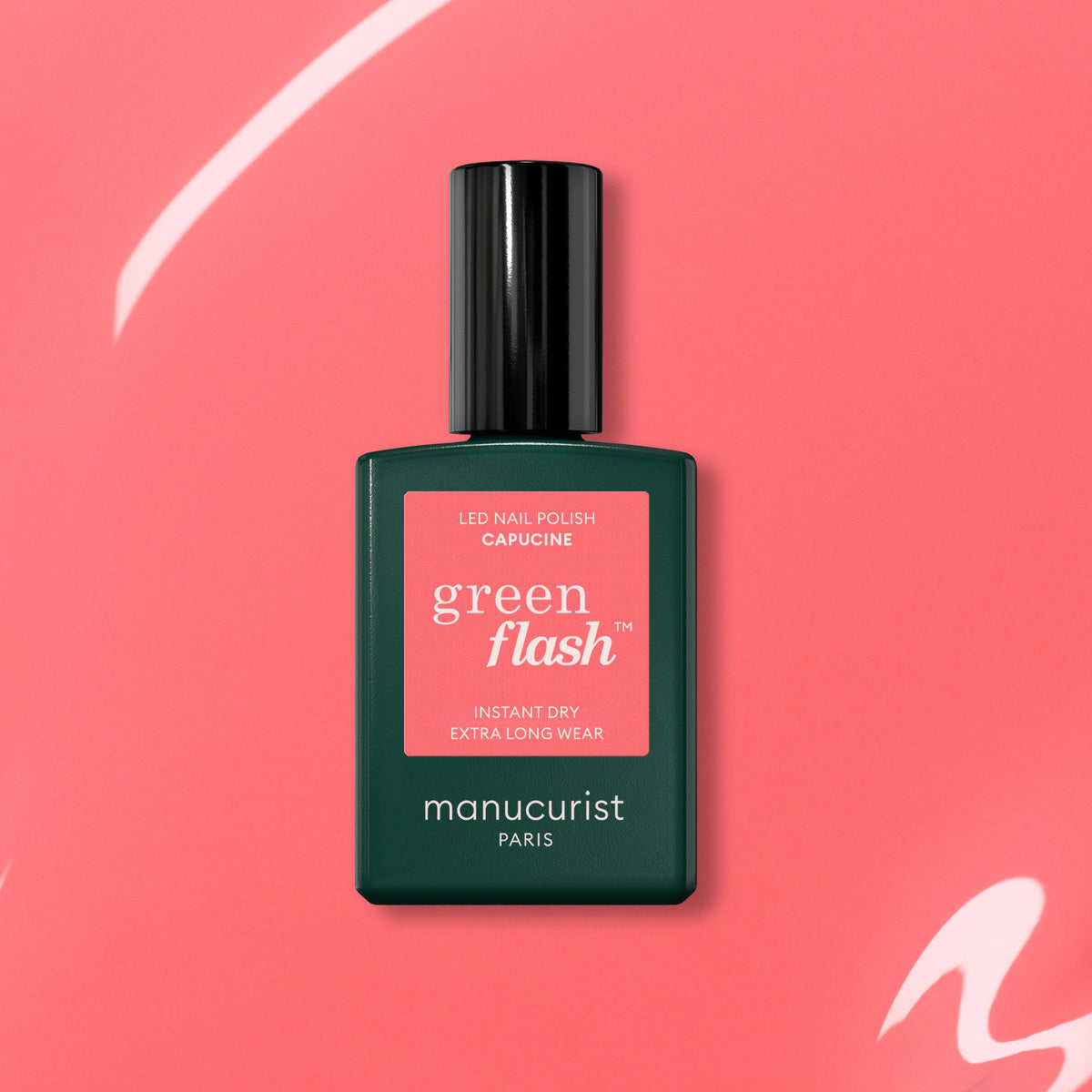 A bottle of Manucurist Capucine Green Flash gel polish with a black cap is set against a coral pink background with white curves. The label highlights "Instant Dry" and "Extra Long Wear," ideal for fans of vibrant pink nail color.