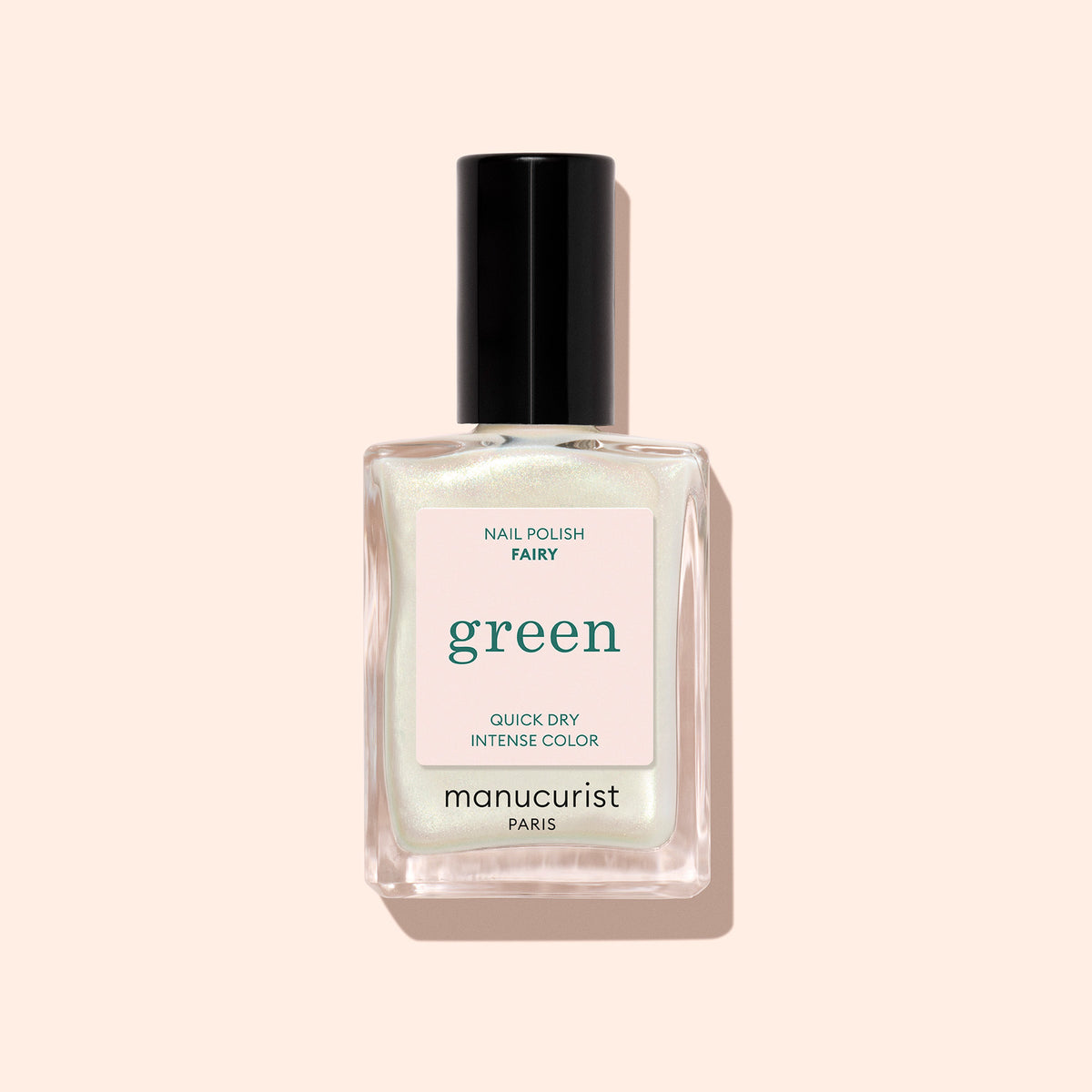 A clear glass bottle of Manucurist Fairy nail polish with a black cap, labeled Quick Dry Intense Color, is shown against a pale peach background.