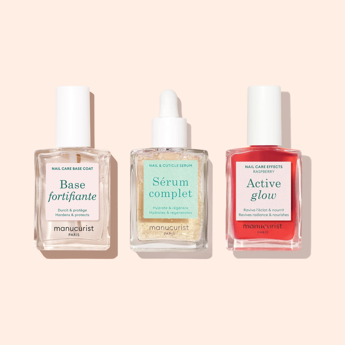 Three bottles of Manucurist’s Routine for Soft Nails are arranged side by side against a light background: a base coat, a serum with dropper, and a red nail polish.