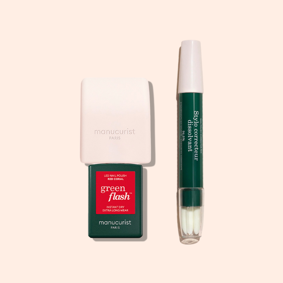 A Manucurist Mani Helper slip corrector pen sits next to a bottle of green flash red coral LED nail polish with a white cap, both perfect for flawless manicure and nail polish application, on a light beige background.