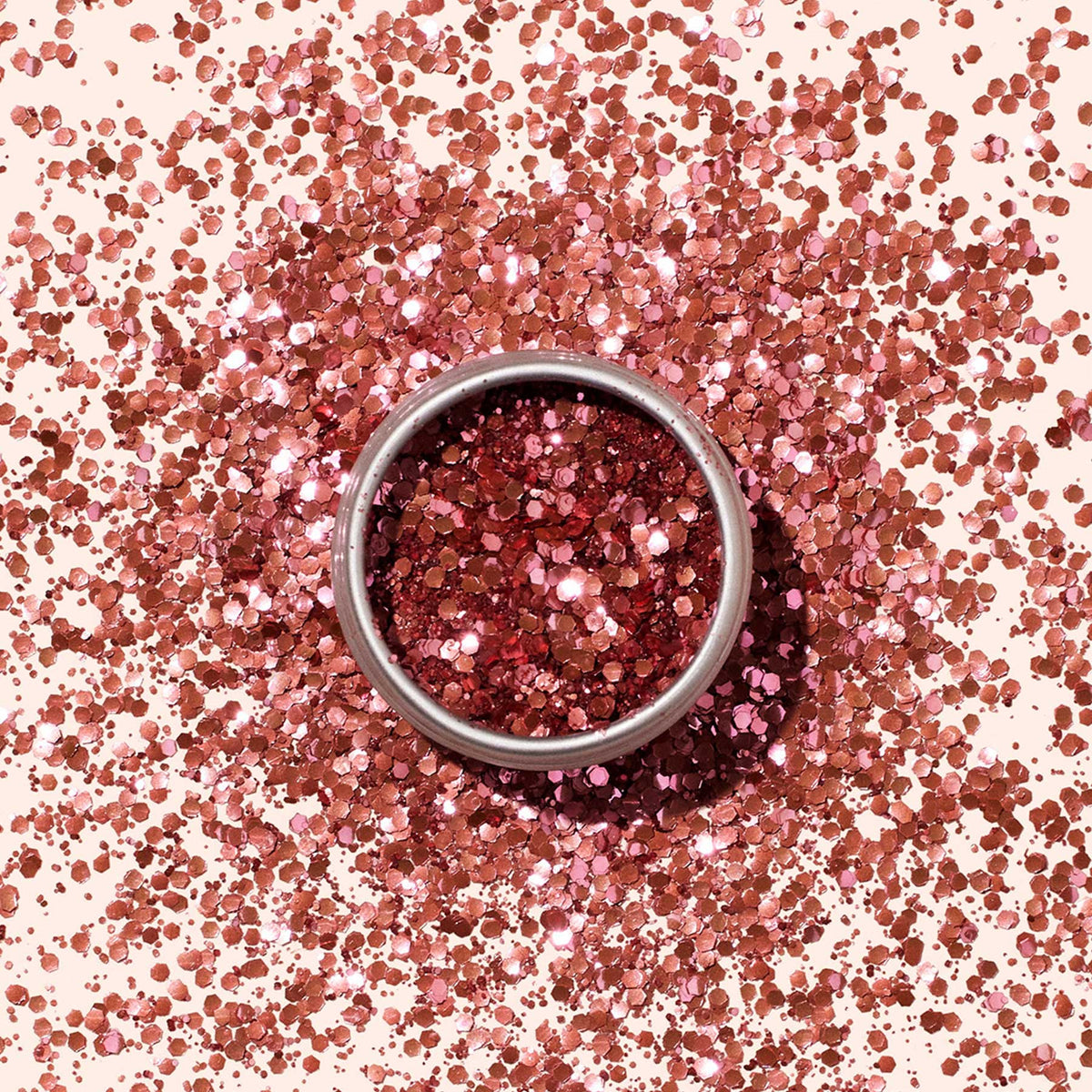 A round Manucurist Biodegradable Glitter container sits on a surface, surrounded by scattered pink glitter—ideal for eco-friendly nail art.