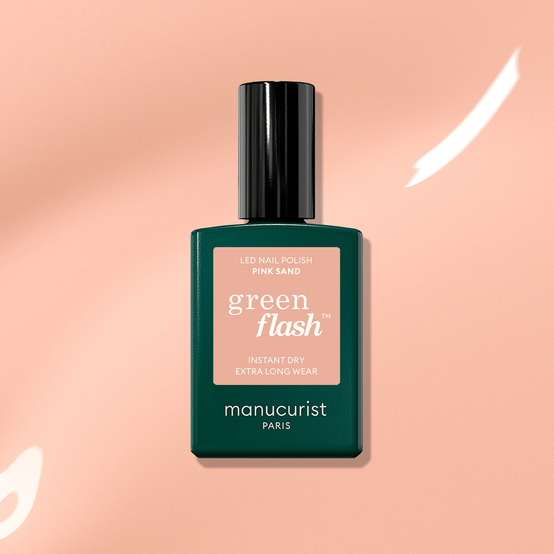 Manucurist’s Pink Sand Green Flash gel nail polish, featuring subtle orange undertones, is shown on a peach background accented with white light reflections.