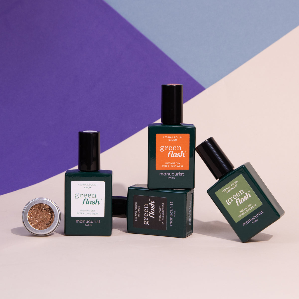 Four bottles of Manucurist Pumpkin Patch gel polish and a small pot of gold glitter powder are arranged on a geometric purple, blue, and beige background—perfect for your next show-stopping nail art set.