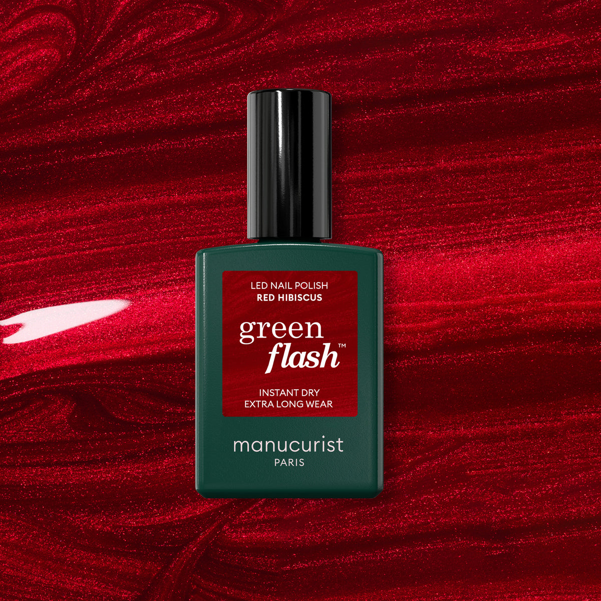 A bottle of Manucurist Red Hibiscus polish rests on a swirling, glossy red background that perfectly matches the vibrant shade of this Green Flash gel color.