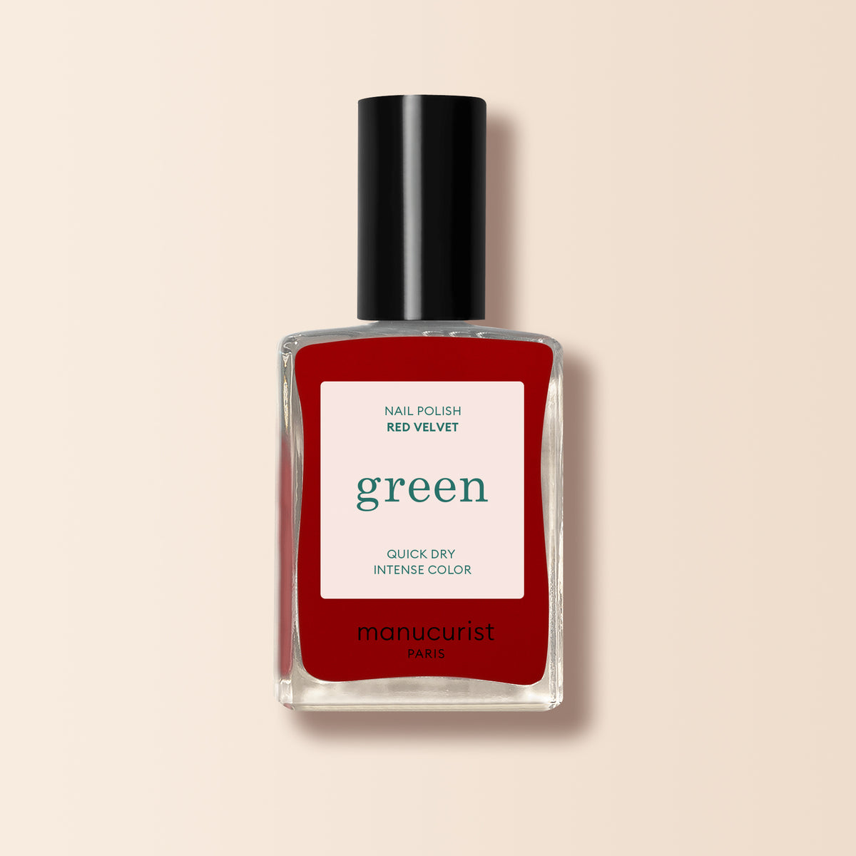 A bottle of Manucurist Red Velvet nail polish from the Green range, featuring a black cap, clear glass, and a white label with "green" and "quick dry intense color," pictured on a light beige background.