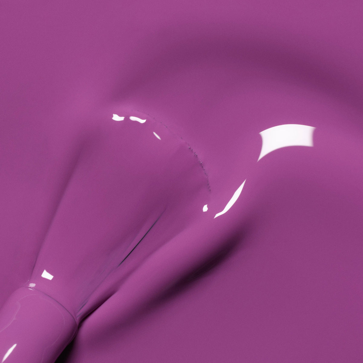 A close-up of a brush spreading glossy purple paint from Manucurist’s Retro Rainbow collection, creating smooth, shiny textures and curved lines across the surface.