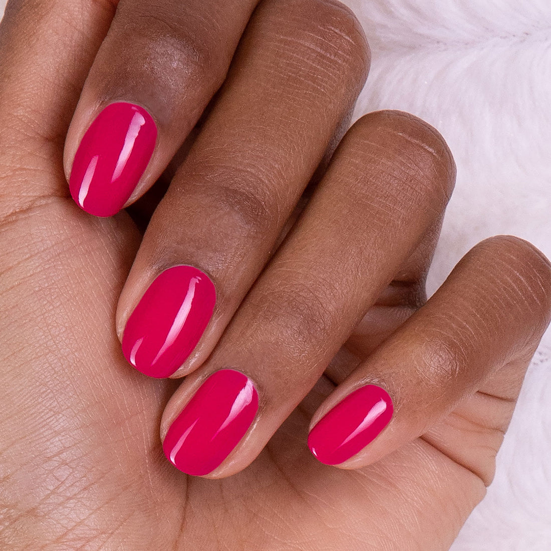 A close-up of a hand with medium brown skin showcases four fingers, each with neatly manicured nails painted in Manucurist&