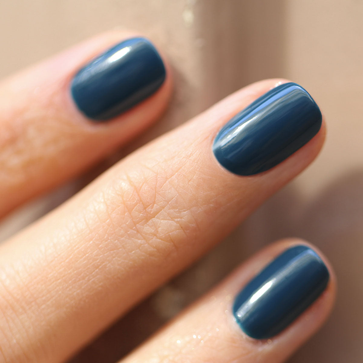 A close-up of a light-toned hand with short, neatly shaped nails painted in Manucurist&