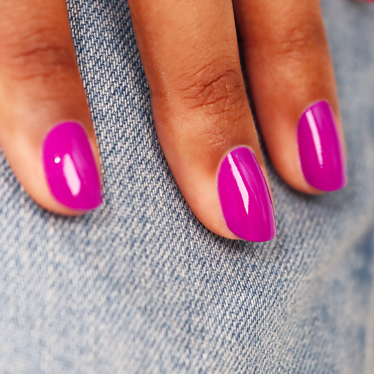 A close-up of a hand with Armeria, a pinky mauve nail polish from Manucurist’s Green™ range, resting on light blue denim fabric.