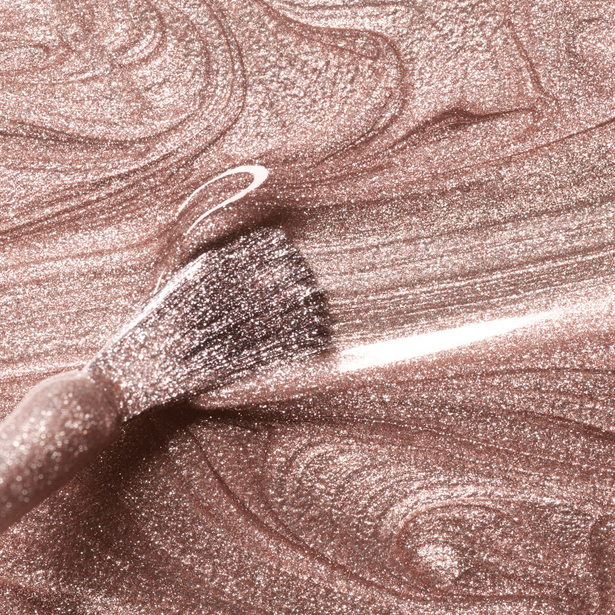 A close-up of Manucurist’s Cosmic Rose brush applying shimmery, champagne pink gel polish with a glittery, swirling texture.