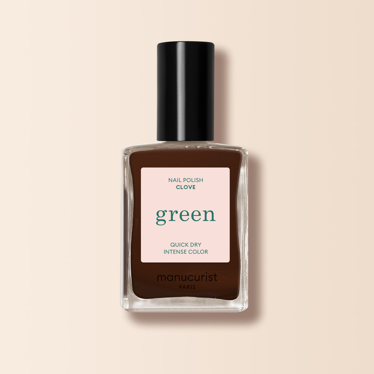 A bottle of Manucurist Clove nail polish, a chocolate brown shade from the Green™ range, features a black cap, beige Quick Dry Intense Color label, and is set against a light beige background.
