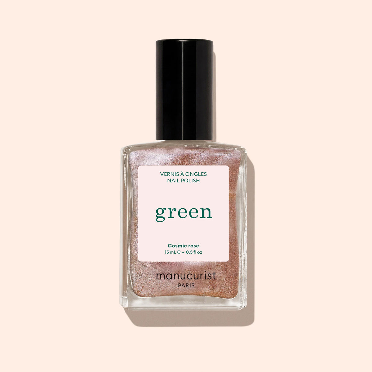 A bottle of Manucurist Cosmic Rose nail polish, an iridescent pink shade from the Green™ range with a black cap, is photographed against a light beige background.