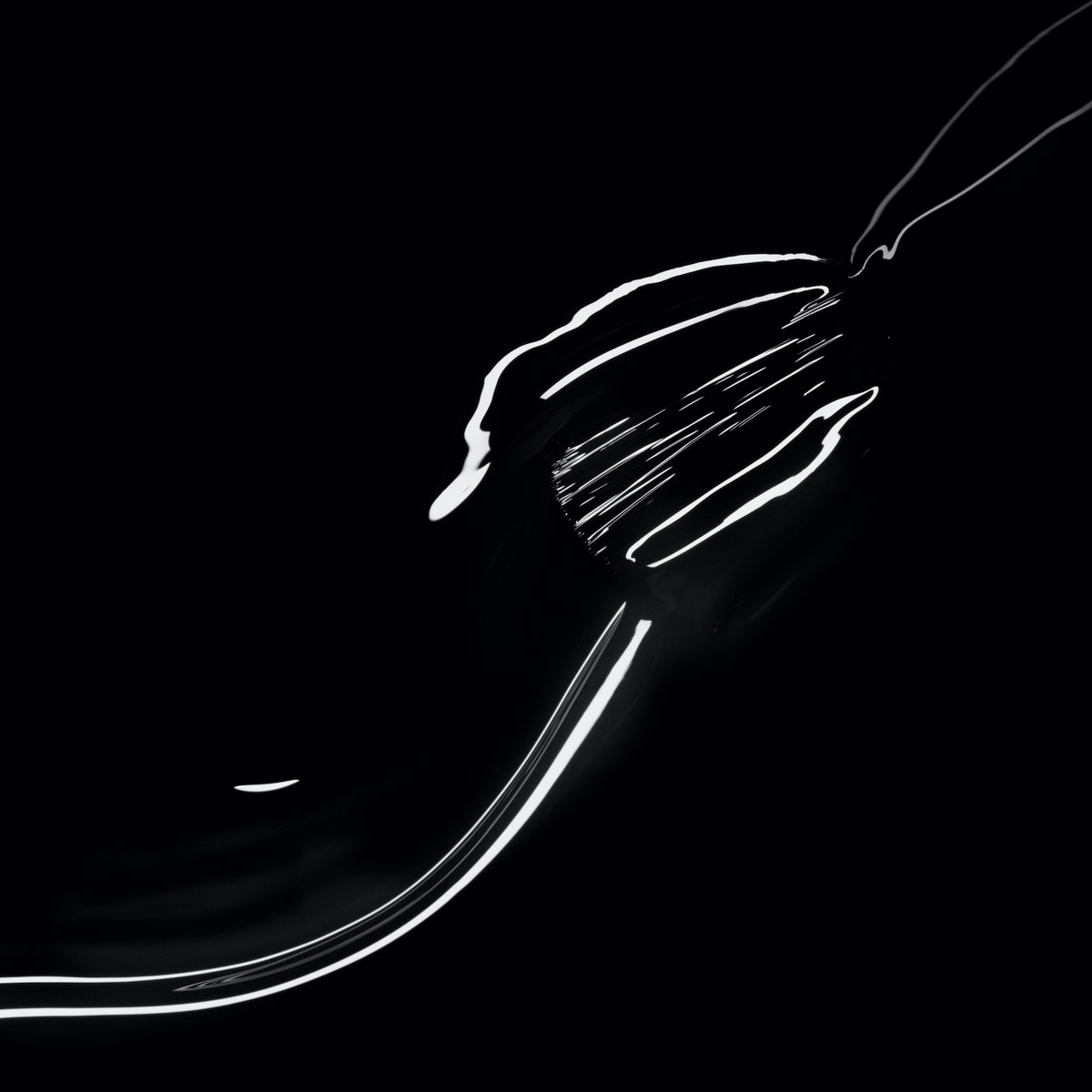 A metal fork is partially visible with bright highlights outlining its shape against a black background—creating an abstract, minimalist composition that mirrors the bold contrast of Manucurist’s Licorice nail polish.