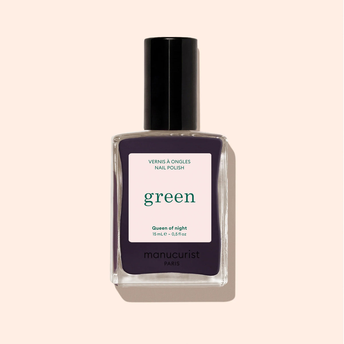 A bottle of Manucurist Queen of Night nail polish, with a bold "green" label and black cap, displayed against a beige background.