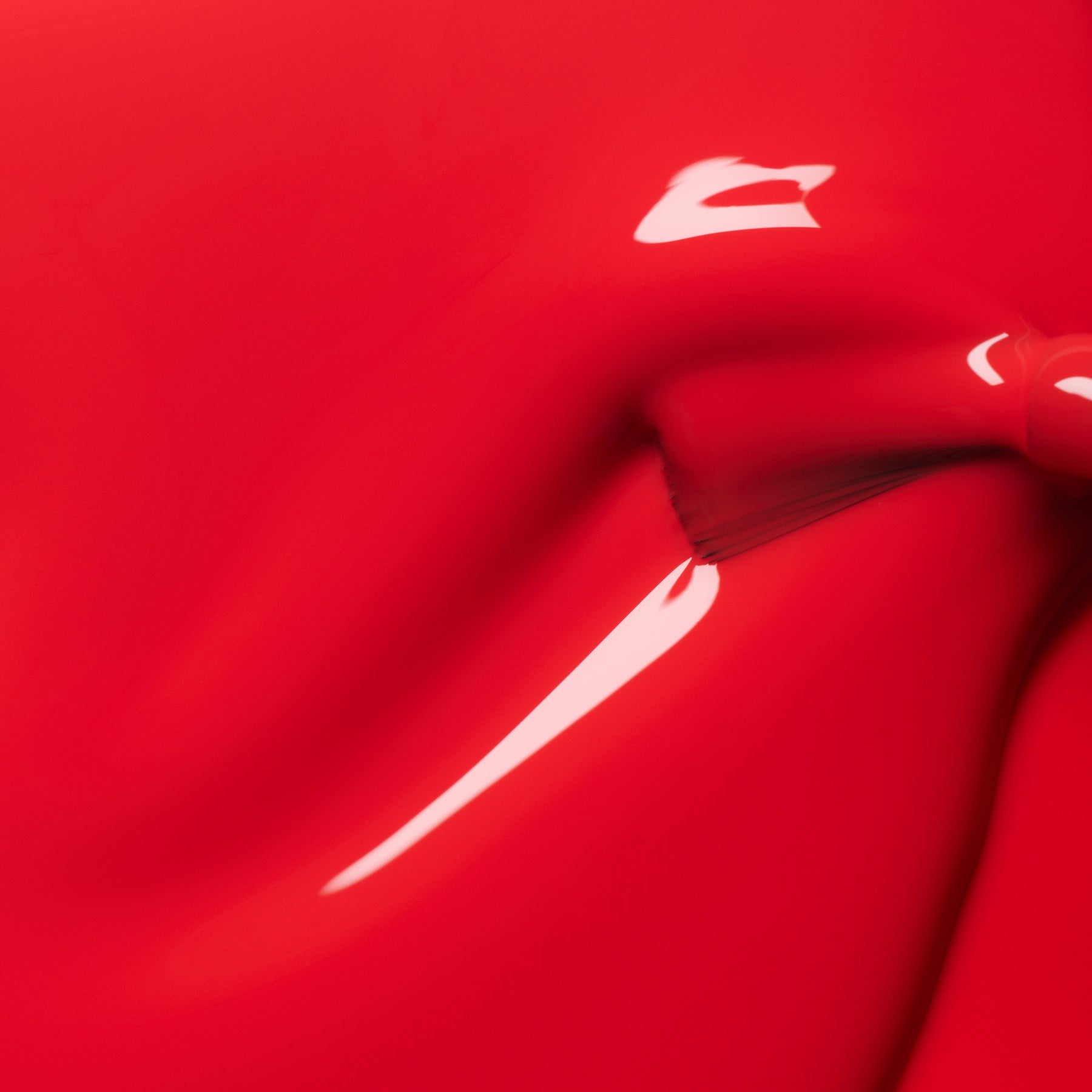 Close-up of Manucurist-test Red Coral OLD glossy LED nail polish being spread smoothly with a brush, revealing shiny highlights and rich, long-lasting color.