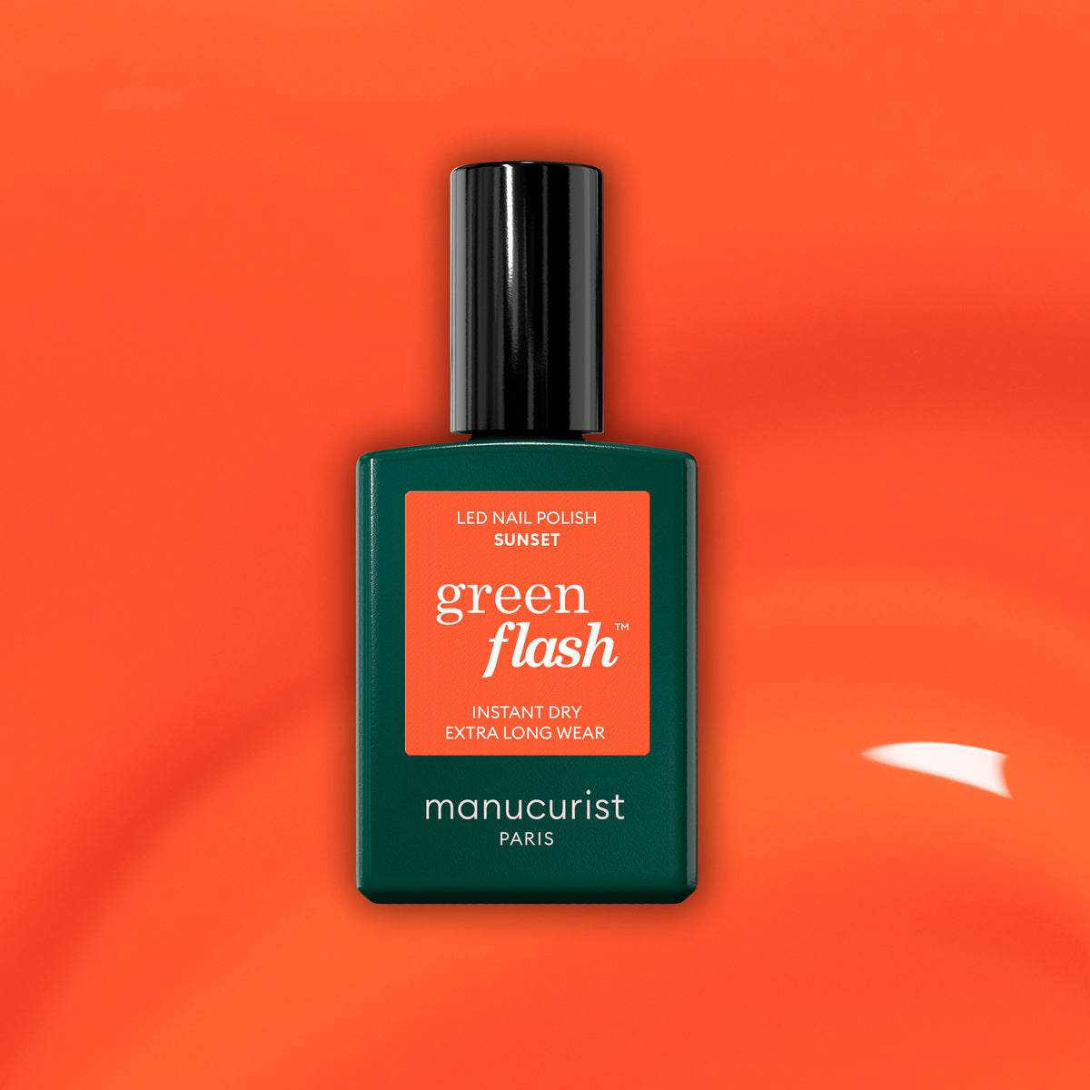 Manucurist’s Green Flash gel polish in the shade Sunset is shown against a glossy, vibrant orange background. The bottle features a dark green design with a black cap and an orange label, accentuating the stunning orange color.