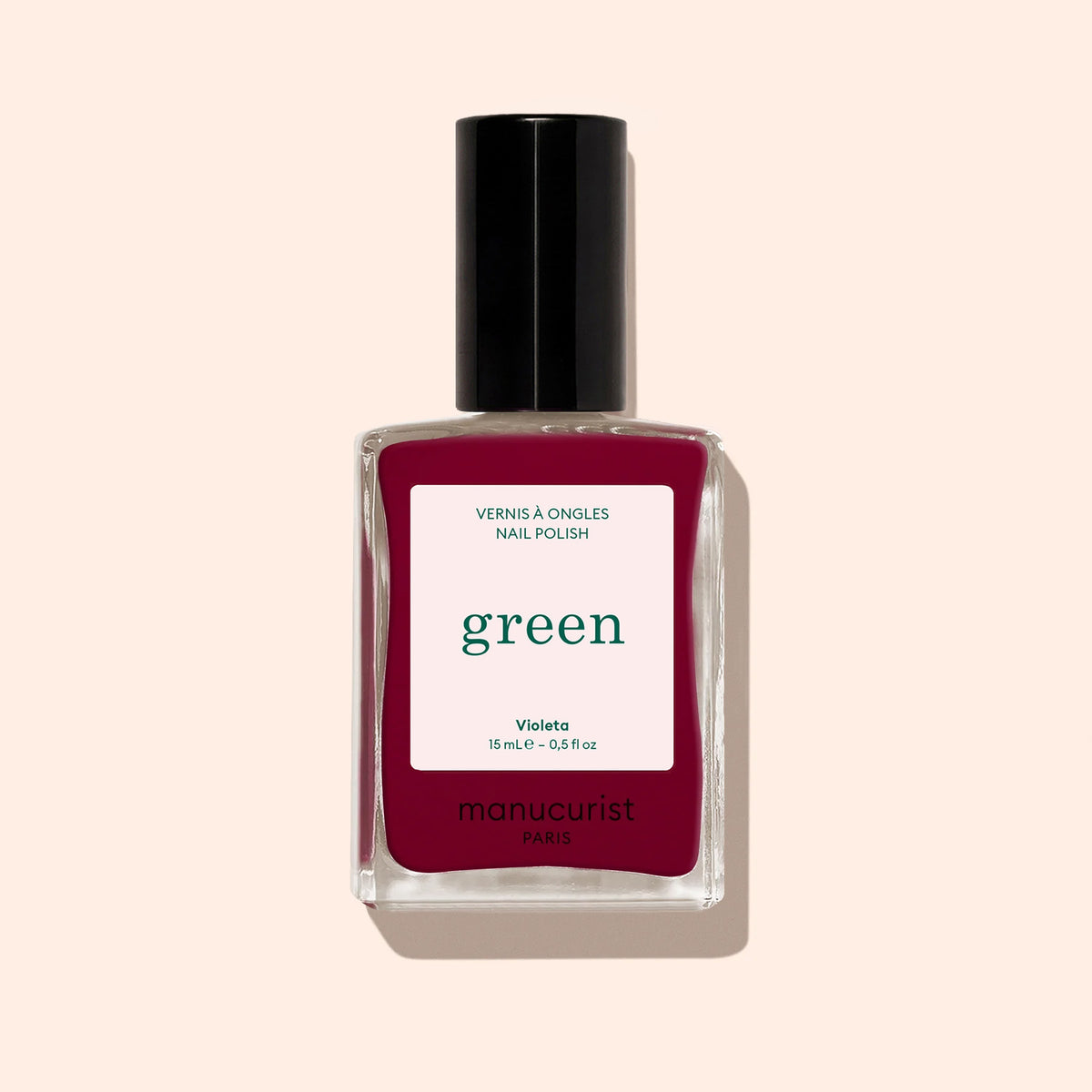 A bottle of Manucurist nail polish in the shade Violeta, a rich burgundy purple, is shown with a black cap against a pale beige background.