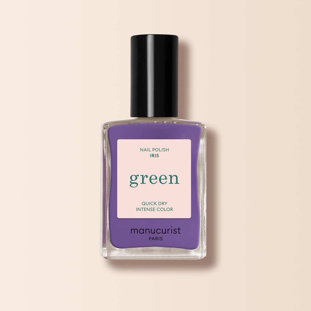 A bottle of Manucurist Iris nail polish, a purple shade with blue undertones from the Green™ range, featuring a black cap and displayed against a light beige background.