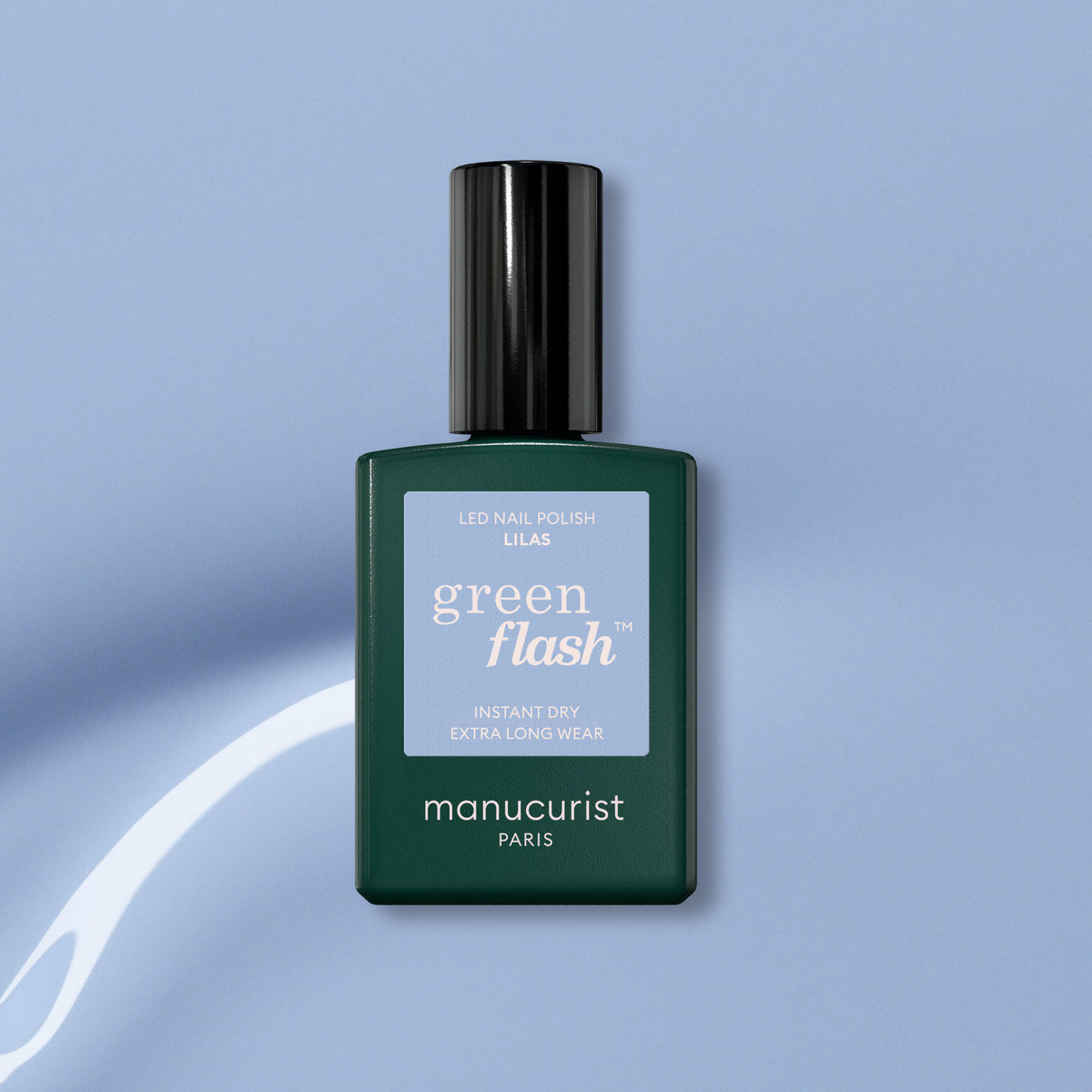 A bottle of Manucurist Lilas Green Flash gel polish, featuring a dark green base and black cap, is displayed on a light blue background with a white swirl design.