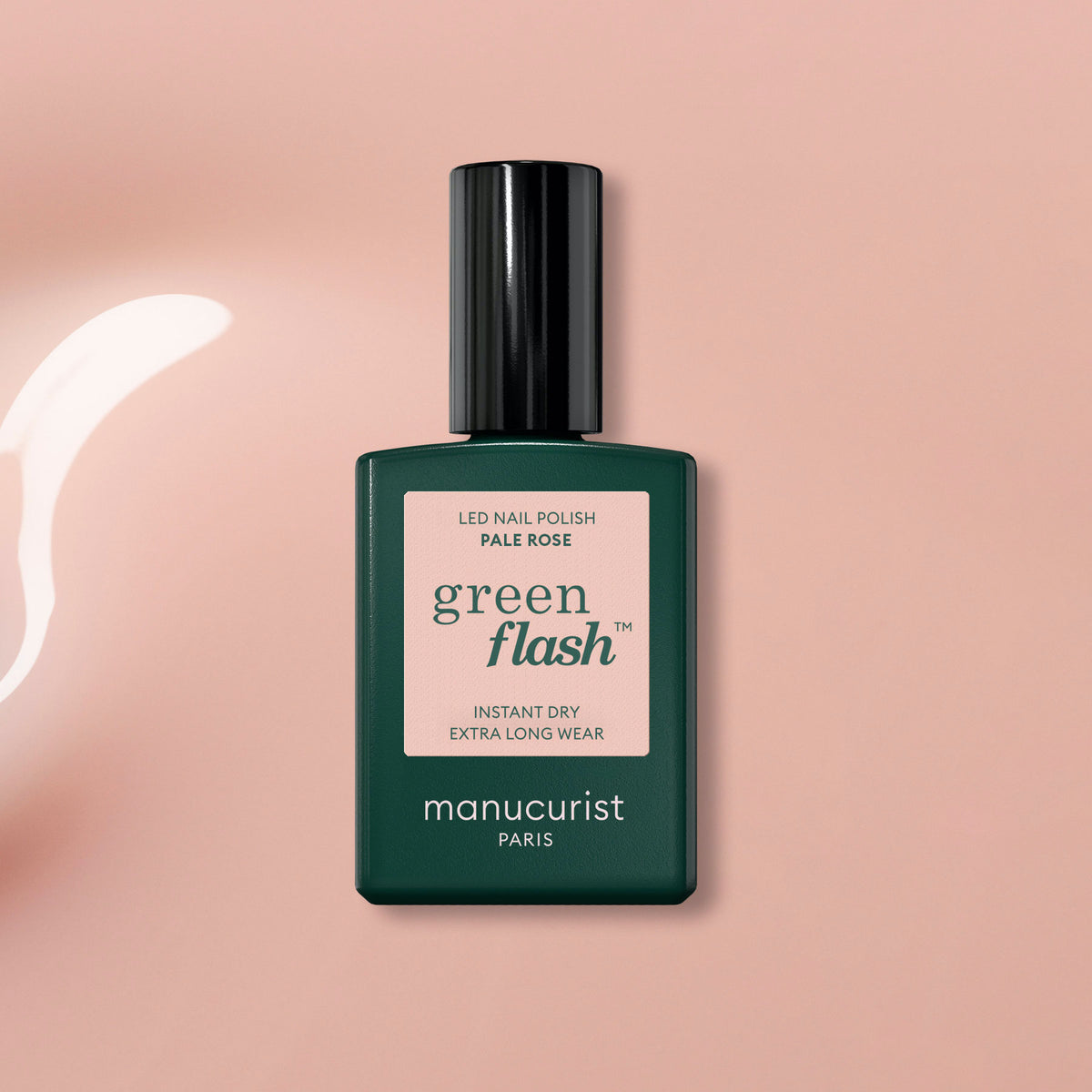A bottle of Manucurist Pale Rose gel polish rests on a light pink surface, with a glossy, soft sheer rose polish spill beside it.