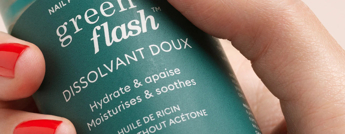 A hand with red nail polish holds a green bottle labeled green flash DISSOLVANT DOUX Hydrate & apaise Moisturises & soothes in white text.