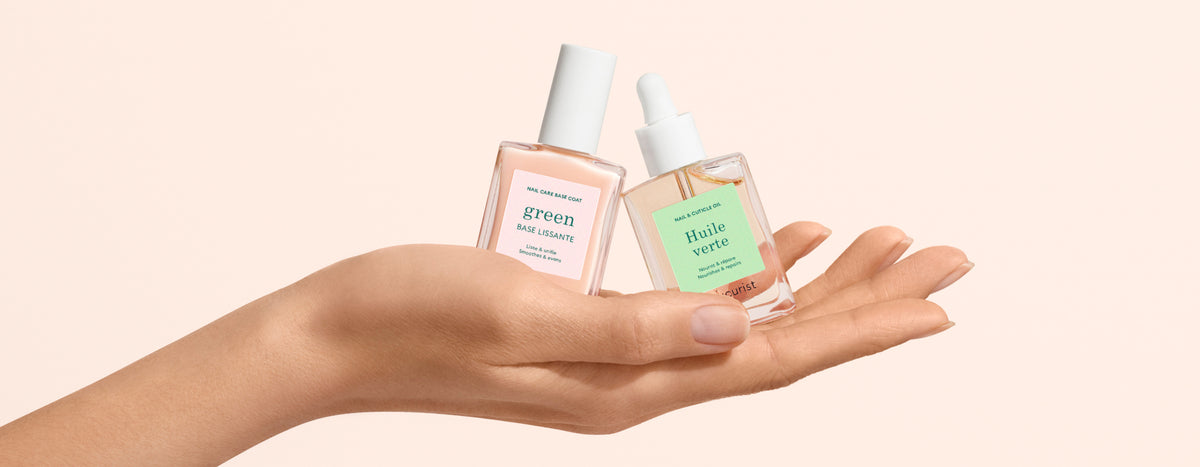 A hand holds two glass skincare bottles with droppers, labeled “green” and “huile verte,” against a light beige background.