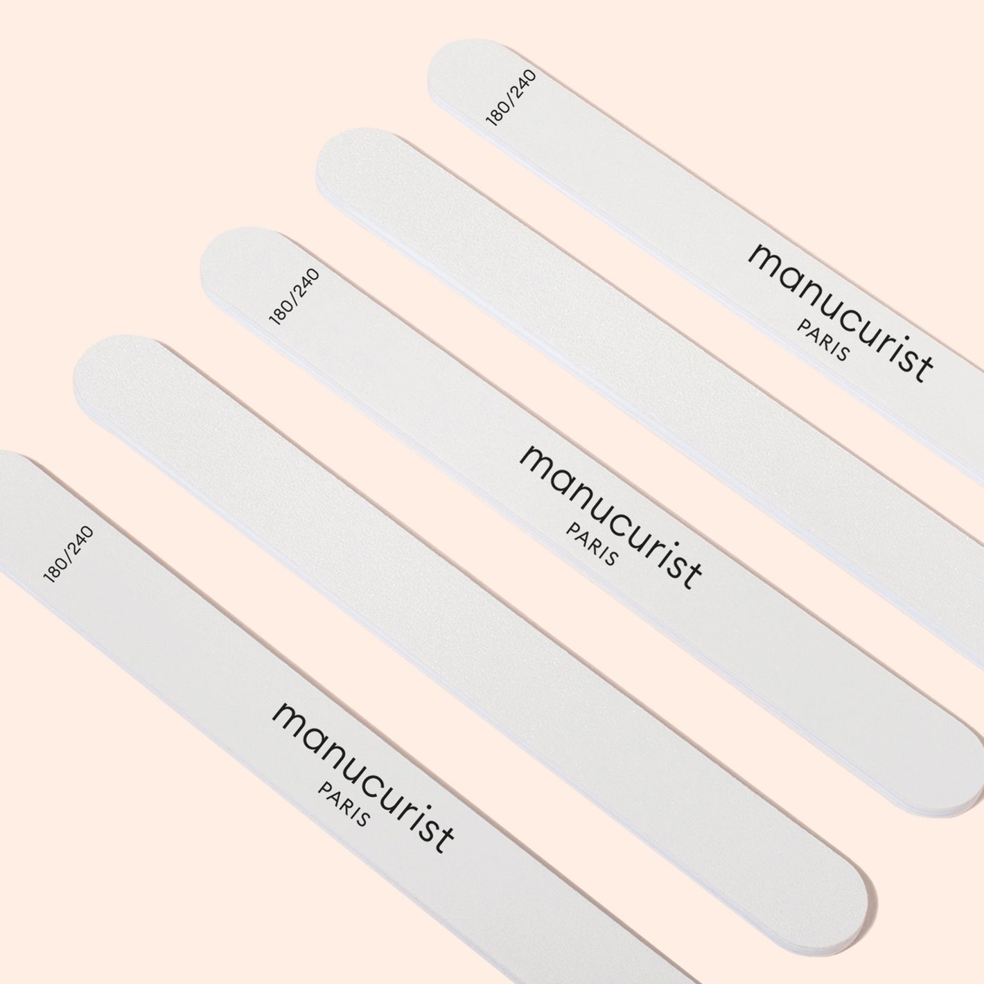 Five Manucurist 180/240 emery boards for fragile nails (pack of 5) are displayed diagonally on a light beige background—ideal for shaping sensitive or brittle nails.