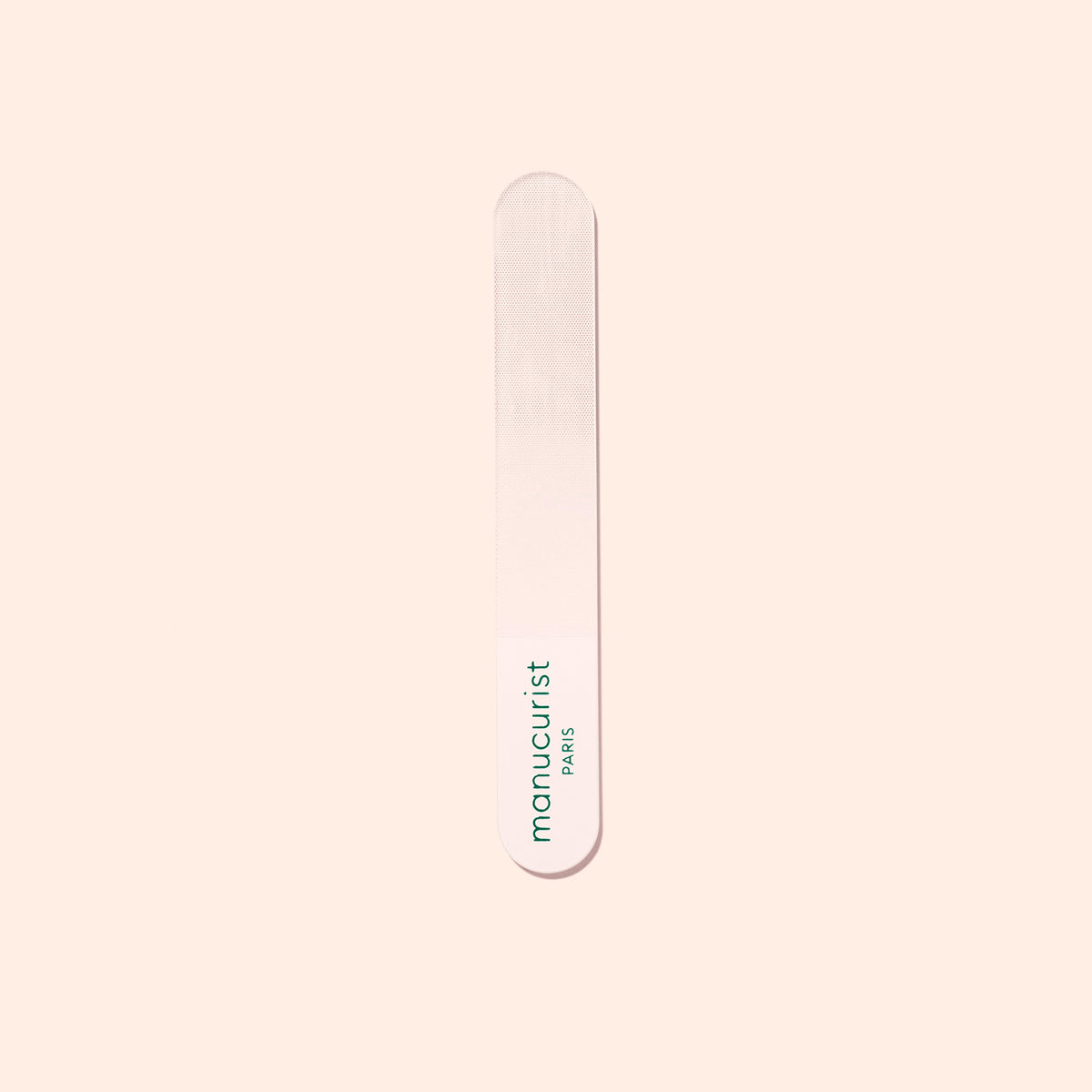 The Manucurist Glass Polisher, ideal for shaping natural nails, has rounded edges and displays "manucurist" and "PARIS" in green text, centered on a light beige background.