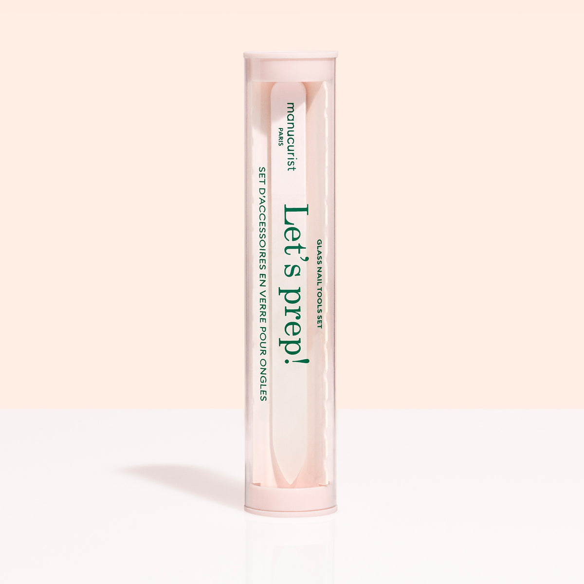 A cylindrical clear container with a pink cap holds the Manucurist Glass Nail Accessory Trio. The label reads "manucurist" and "Let&