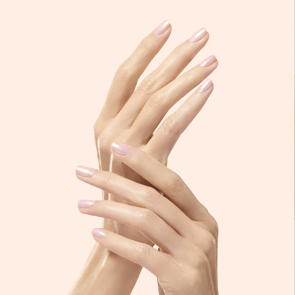 Two hands with neatly manicured nails painted pale pink, enhanced by Manucurist&