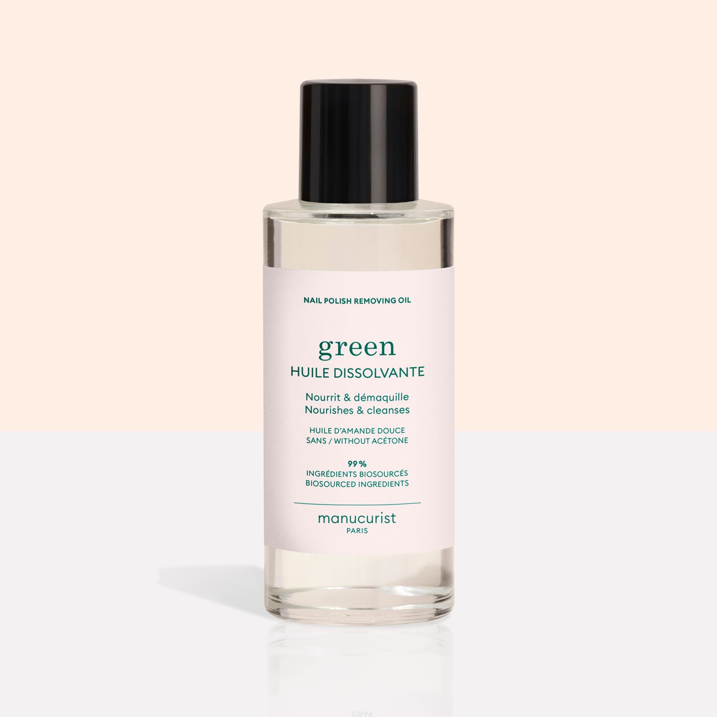 A clear bottle with a black cap contains Manucurist Green Nail Polish Removing Oil. Its light pink label, with green and blue text, highlights this plant-based, acetone-free formula as gentle and biobased.