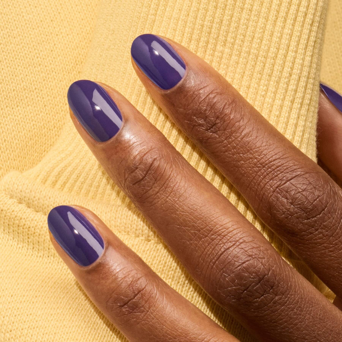 A hand with dark skin and neatly manicured nails painted in Manucurist&
