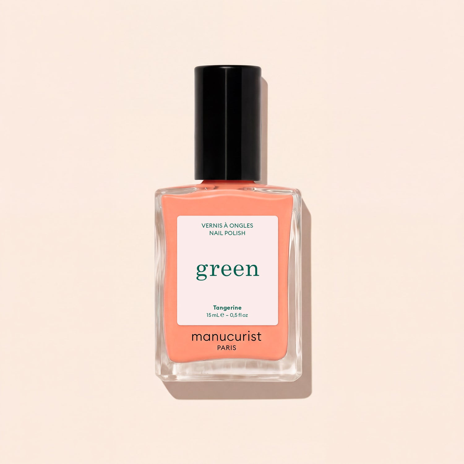 A bottle of Manucurist Tangerine nail polish, a neon light orange shade, features a black cap and minimalist label, displayed on a light beige background.