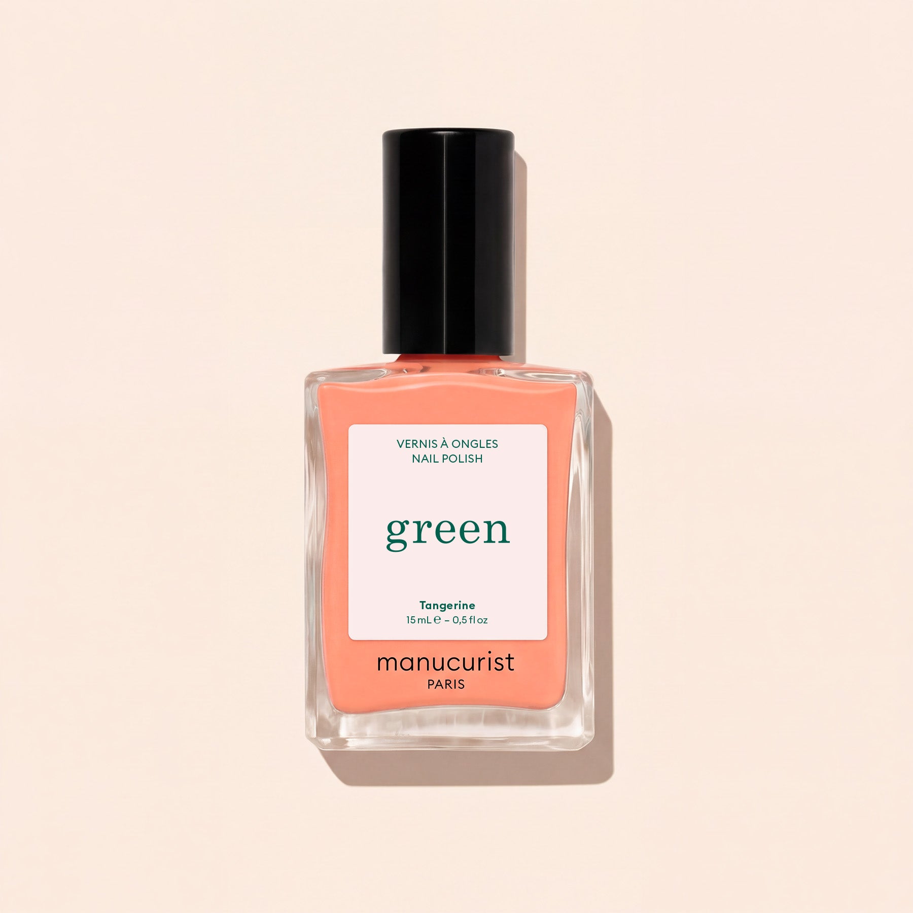 A bottle of Manucurist Tangerine nail polish, a neon light orange shade, features a black cap and minimalist label, displayed on a light beige background.
