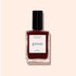 A bottle of Manucurist Grenat red nail polish with a black cap, labeled green and Green™, sits on a light beige background.