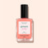 A bottle of Manucurist Glacé ultra-glossy jelly nail polish in coral pink with a black cap, shown against a light peach background.