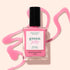 A bottle of Manucurist Pink Sorbet Jelly nail polish stands on a beige surface, surrounded by swirling translucent pink polish.