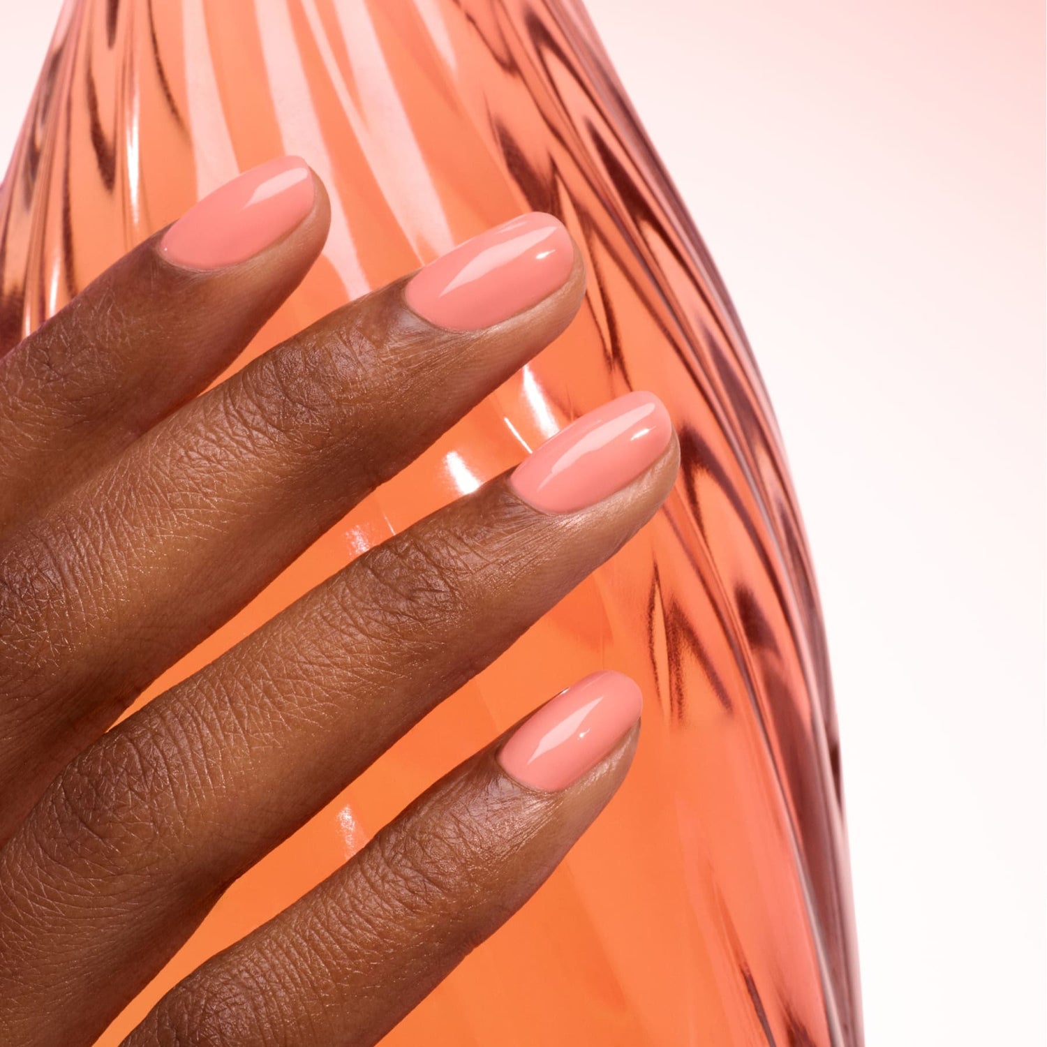 A hand with neatly manicured, ultra-glossy peach nails—painted with Manucurist&